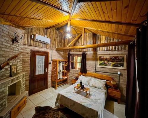 un salon avec un lit et une cheminée dans l'établissement Aldeia Pé da Serra Cabana Natureza, à Três Coroas