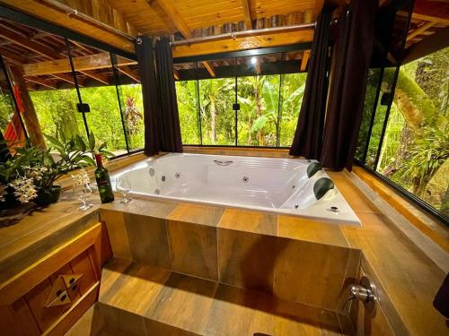 Cette chambre dispose d'une grande baignoire et de fenêtres. dans l'établissement Aldeia Pé da Serra Cabana Natureza, à Três Coroas