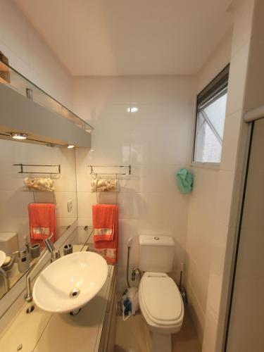 a bathroom with a white toilet and a sink at Apto 2 quartos - 250 m da praia de Atlântida in Xangri-lá