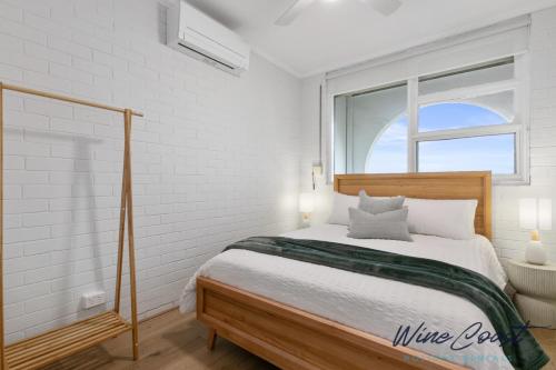 um quarto branco com uma cama e uma janela em Wave N Sea Shore by Wine Coast Holidays em Christies Beach