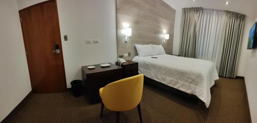 a hotel room with a bed and a yellow chair at LA TERRAZA INN in Huancavelica