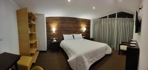 a hotel room with a white bed and a desk at LA TERRAZA INN in Huancavelica