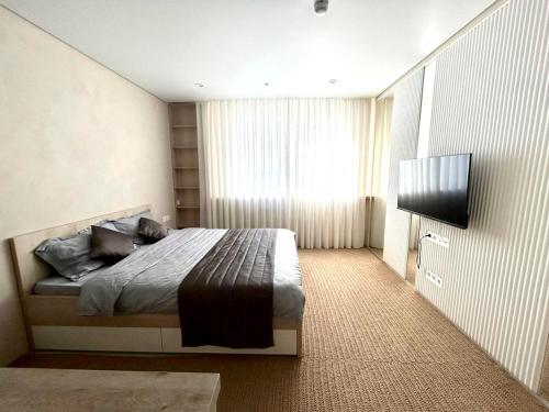 a bedroom with a bed and a flat screen tv at Апарт-отель напротив ботанического сада in Astana