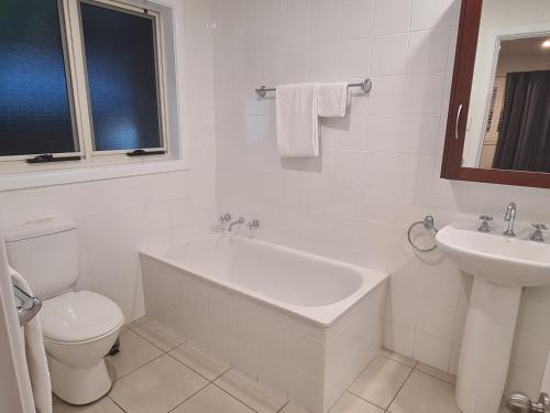 a white bathroom with a toilet and a sink at Moore Park Apartments in Armidale