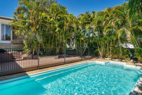 a swimming pool with a fence and palm trees at Tropical 2-bedroom Guesthouse, Pool, Sauna in Tanah Merah