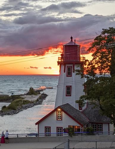 a lighthouse in front of the ocean at sunset at Inn at the Harbour in Kincardine