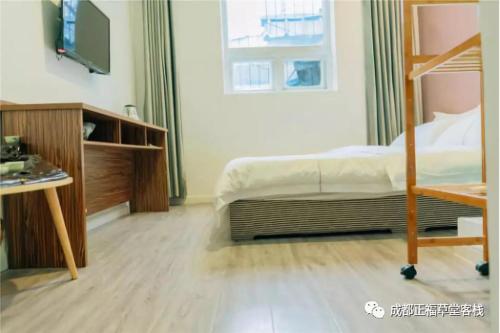 een slaapkamer met een bed, een bureau en een televisie bij Chengdu Zhengfu Cao Tang Inn in Chengdu