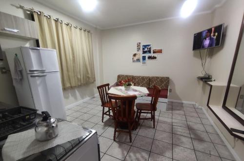 cocina con mesa, sillas y nevera en Afonso Cardoso da Veiga, en Florianópolis