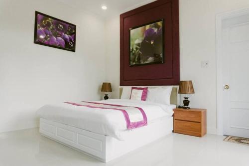 een witte slaapkamer met een bed en 2 lampen bij Flower Hill in Da Lat
