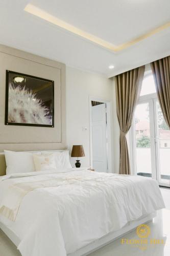 a white bedroom with a white bed and a window at Flower Hill in Da Lat
