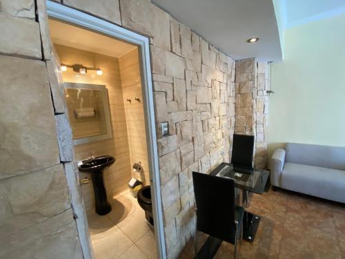 uma casa de banho com uma parede de pedra, um lavatório e um sofá. em AH Teatinos em Santiago