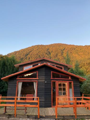 a black cabin with two benches in front of it at CABAÑAS RUCA MALAL in Futrono