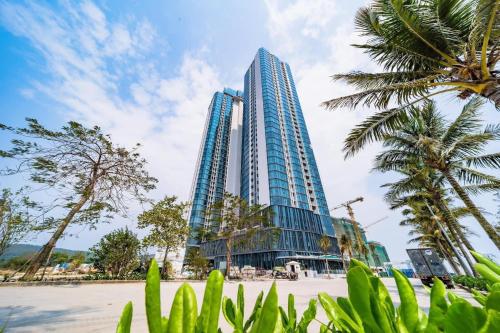 um edifício alto com palmeiras em frente em Khách sạn A La Carte Hạ Long-Quảng Ninh em Ha Long