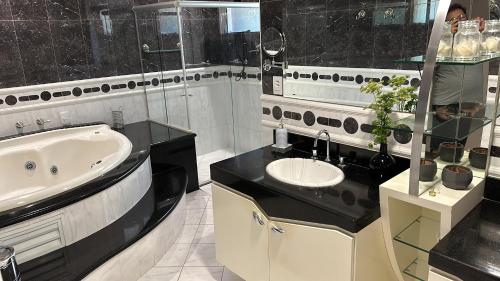 a black and white bathroom with a sink and a tub at Job&Joy Business Hostels in Campinas