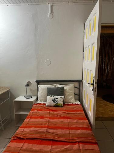 een slaapkamer met een bed met een oranje deken bij O Logis citron du Morne Jacob, Le Morne-Rouge Martinique in Le Morne Rouge