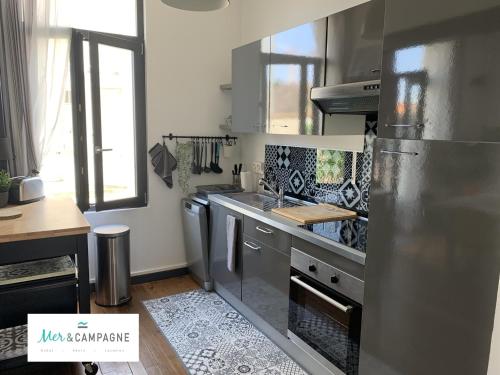 une cuisine avec des appareils en acier inoxydable et un comptoir dans l'établissement Maison rénovée 10 pers à Fort-Mahon-Plage, à 150m de la plage - FR-1-482-84, à Fort-Mahon-Plage