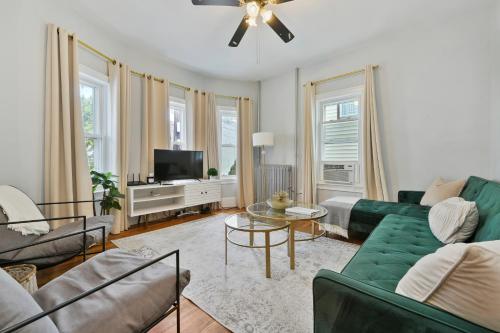a living room with a green couch and a tv at The Maverick Downstairs - Lux Apartment - Close to Downtown Boston & Airport in Chelsea