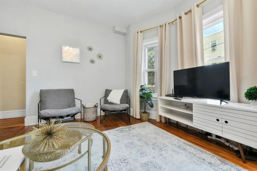 a living room with a television and a table and chairs at The Maverick Downstairs - Lux Apartment - Close to Downtown Boston & Airport in Chelsea