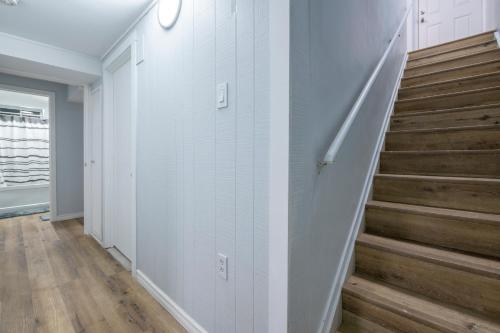 a hallway with white walls and stairs with wood floors at CenterStreet-Cozy 1bedroomSuite in Calgary