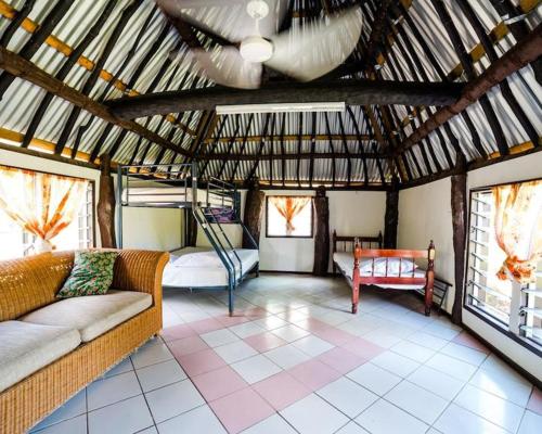 Mana Backpackers and Dive Resort في جزيرة مانا: غرفة معيشة مع أريكة وسرير في مبنى