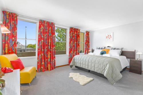 a bedroom with a bed and a chair and windows at #9 Dream in Rotorua