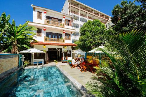 a hotel with a swimming pool in front of a building at B'Lan Riverside Villa in Hoi An