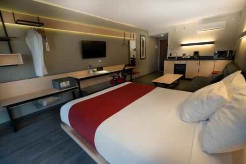 a hotel room with a large bed and a living room at City Express by Marriott Santiago Aeropuerto in Santiago