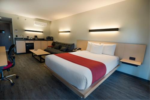 a bedroom with a large bed and a living room at City Express by Marriott Santiago Aeropuerto in Santiago