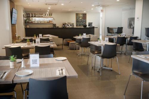 a restaurant with tables and chairs and a bar at City Express by Marriott Santiago Aeropuerto in Santiago