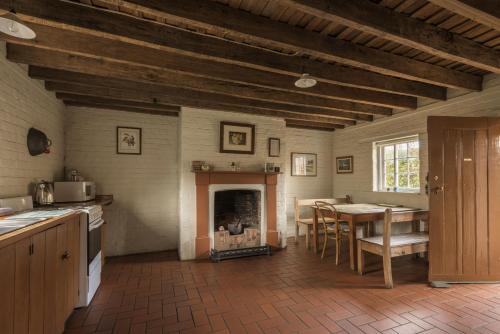 a kitchen and dining room with a table and a fireplace at Woolmers Estate in Longford