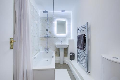 a white bathroom with a tub and a sink at London Central in London