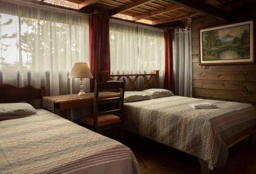 1 dormitorio con 2 camas y mesa con lámpara en Vista Turrialba Lodge, en Turrialba