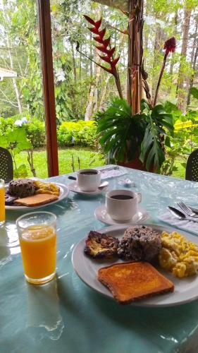 a table topped with plates of food and orange juice at Vista Turrialba Lodge in Turrialba