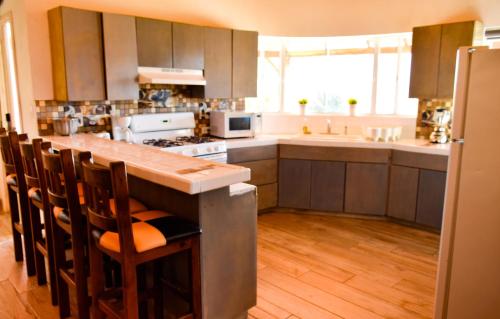 a kitchen with a long counter with chairs in it at Finca Selah in Ensenada