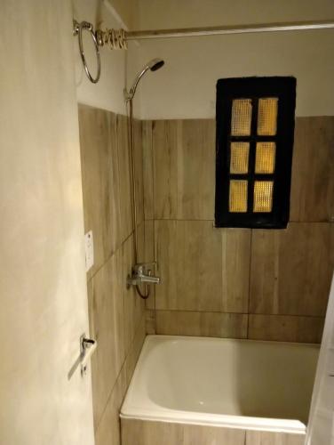 y baño con bañera y ventana. en Cabañas las palmeras en Don Torcuato