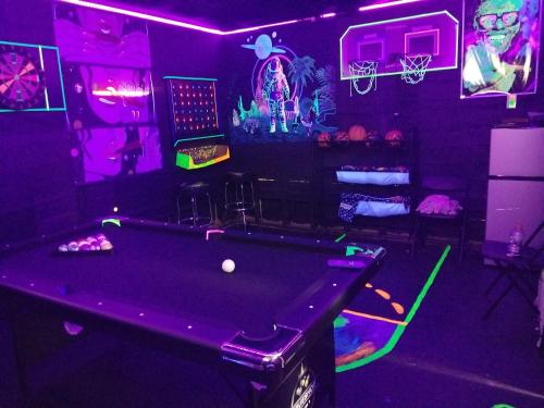 a pool table in a room with purple lights at Cozy 6 bedroom home with Gameroom and Fire pit. in Rawsonville
