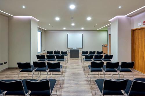 a conference room with chairs and a projection screen at City Express Plus by Marriott Mexicali in Mexicali