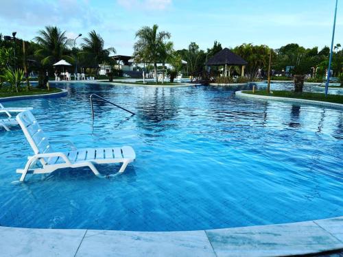 - une piscine avec une chaise blanche dans l'eau dans l'établissement Ap. Vista pra piscina - Iloa, à Barra de São Miguel