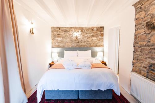 een slaapkamer met een wit bed en een stenen muur bij Stone Barn in Skibbereen