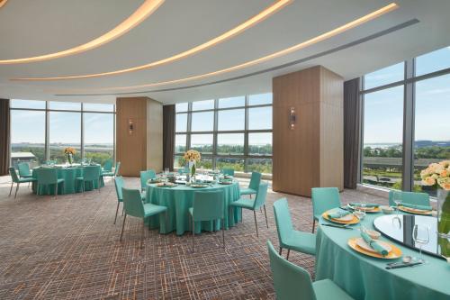 a banquet room with tables and chairs and windows at Hyatt Regency Changshu Kuncheng Lake in Changshu