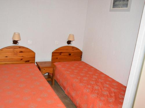 - 2 lits dans une petite chambre avec des draps orange dans l'établissement Appartement cosy avec balcon, parking et piscine à 300m du centre et 500m des pistes - FR-1-464-223, à Pralognan-la-Vanoise