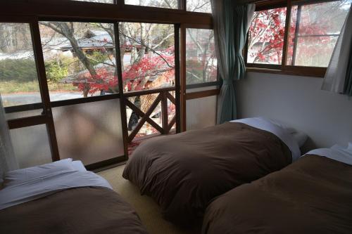 two beds in a room with a window at ペンション イメージハウス in Hara