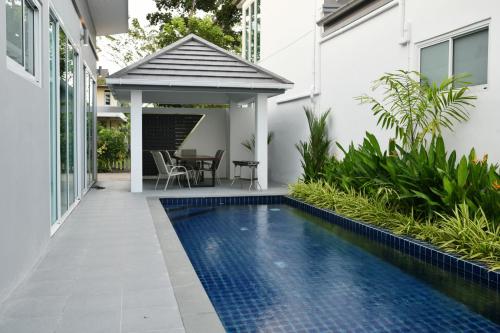 a swimming pool in front of a house with a gazebo at Green Lung Pool Villas Bangkok in Bang Krasop