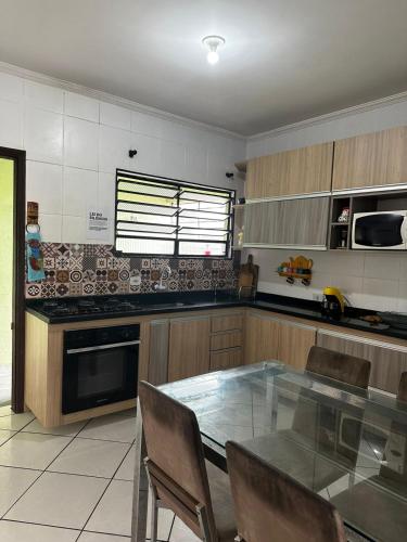 a kitchen with a glass table and chairs at Casa Al Mare in Itanhaém