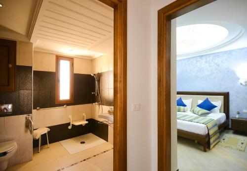 a hotel room with a bed and a bathroom at Palm Djerba Suites in Mezraya