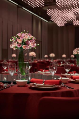 a table with a vase filled with pink flowers on it at Hyatt Regency Changshu Kuncheng Lake in Changshu