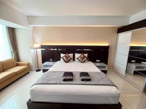 - une grande chambre avec un grand lit et un canapé dans l'établissement The Cabin Mataram City, à Kejayan