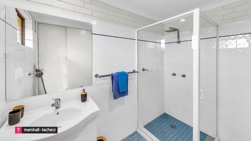 a white bathroom with a shower and a sink at Bermagui River View - Unit 1,1 Lindo Street 3 bdrm Villa in Bermagui