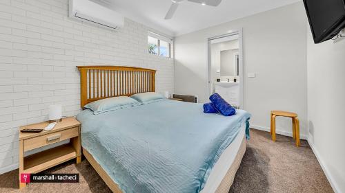 a bedroom with a large bed with a wooden headboard at Bermagui River View - Unit 1,1 Lindo Street 3 bdrm Villa in Bermagui