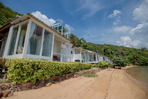a house on the beach next to the water at Seashell Village Resort in Chao Lao Beach